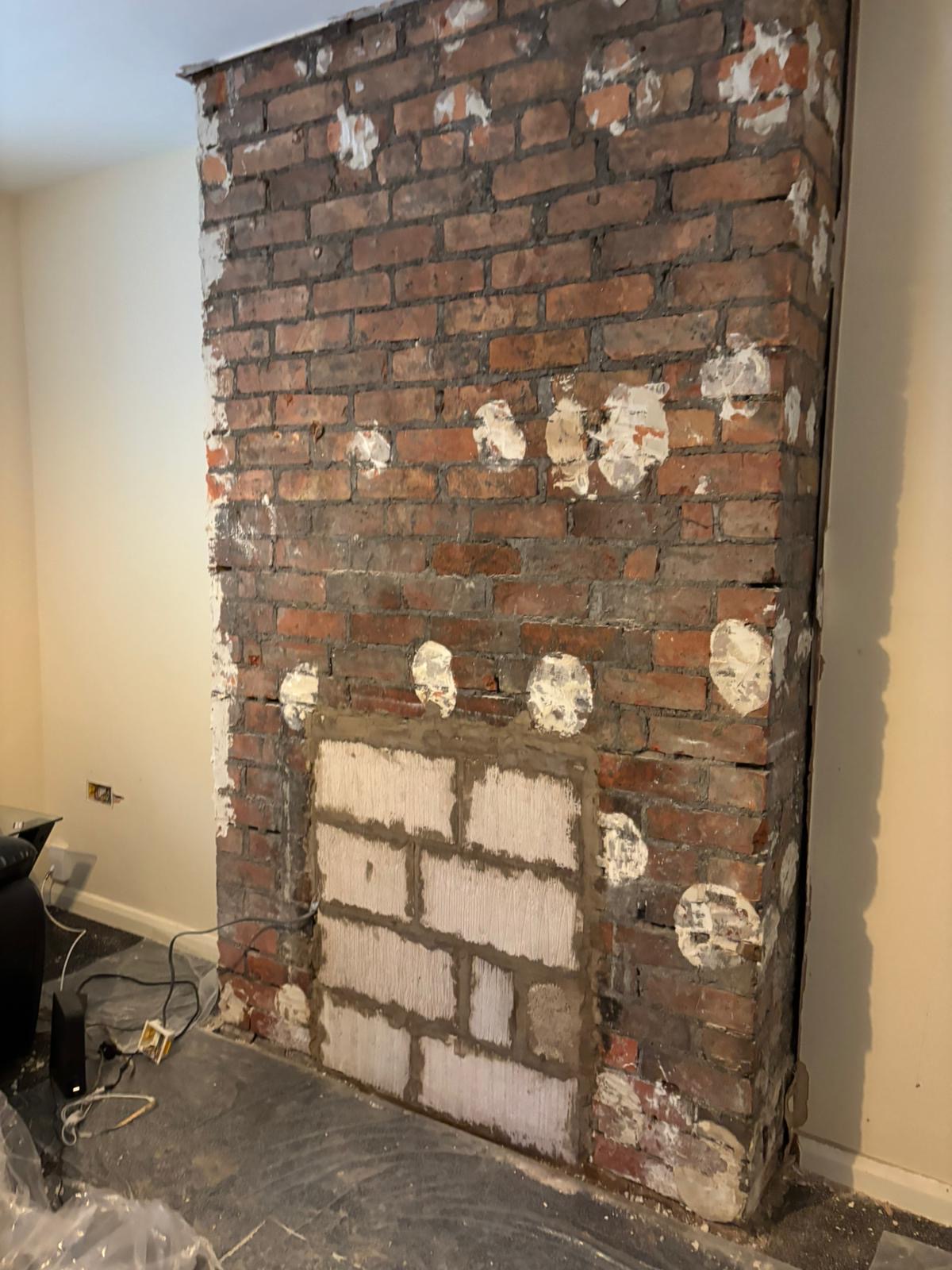 Chimney breast stripped to brick with patches, drying out